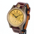 A vintage-style wristwatch with a round bronze-toned case, a gold dial featuring a central floral emblem and black Arabic numerals, and a dark brown leather strap with white stitching.