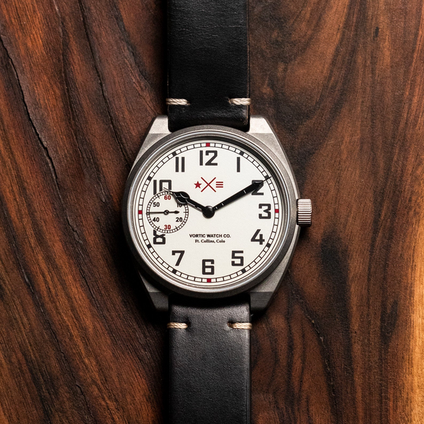 Wristwatch with black strap on a wooden surface