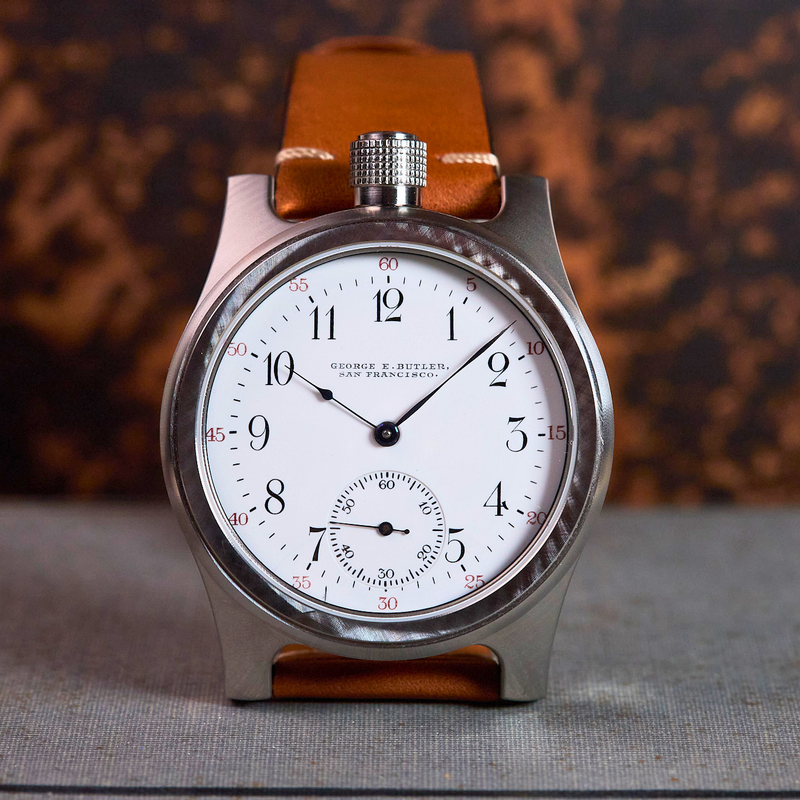 Vintage-style wristwatch with brown leather strap on a textured surface