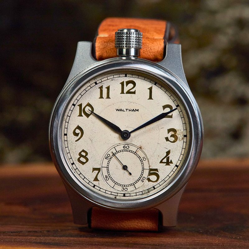 Vintage-style wristwatch with brown leather strap on a wooden surface