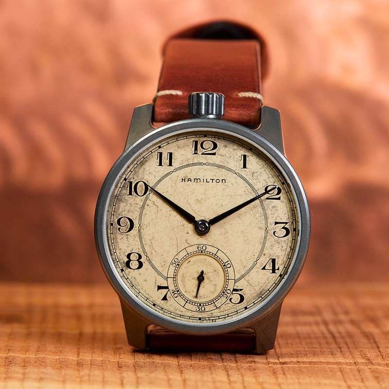Vintage-style watch with brown leather strap on a wooden surface