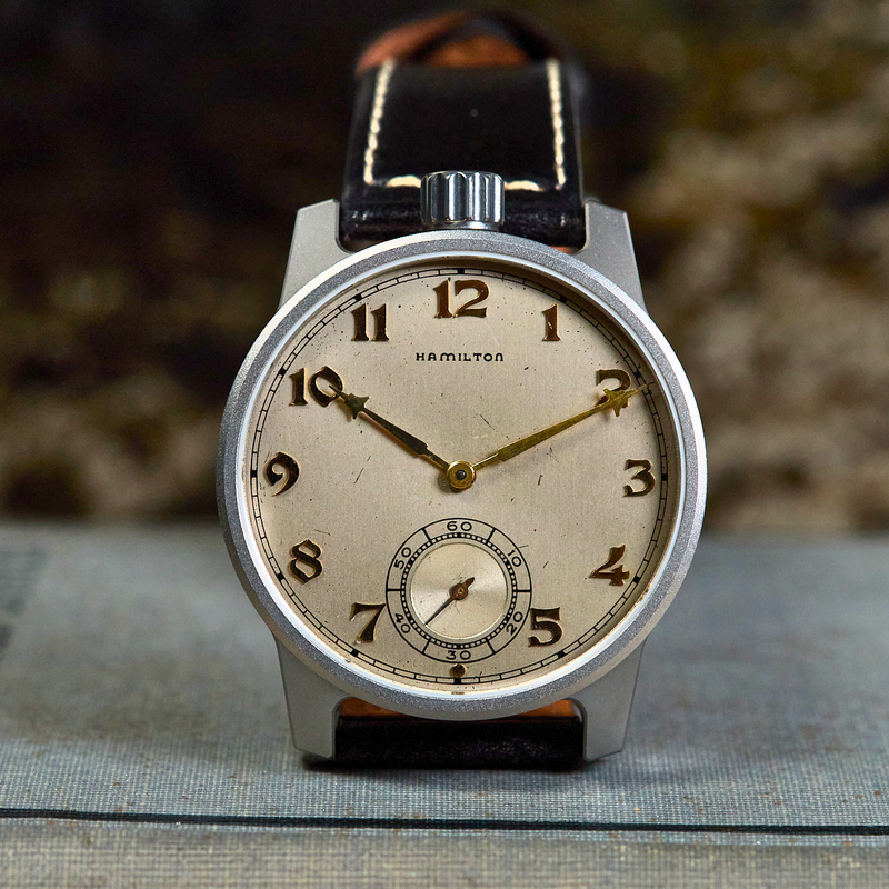 Vintage wristwatch with brown leather strap on a textured surface