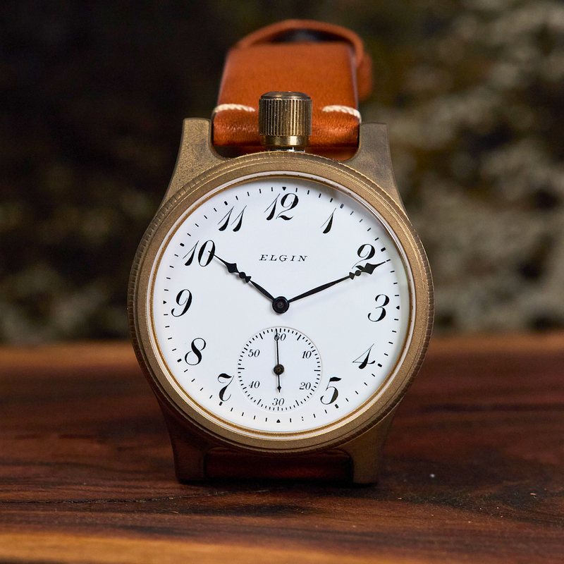 Vintage-style watch with brown leather strap on a wooden surface