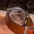 Watch with brown leather strap on a wooden surface