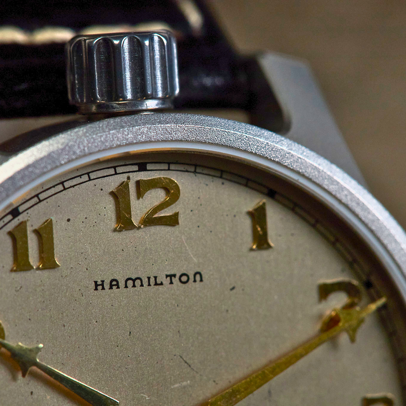 Close-up of a Hamilton watch face with gold numbers and hands.