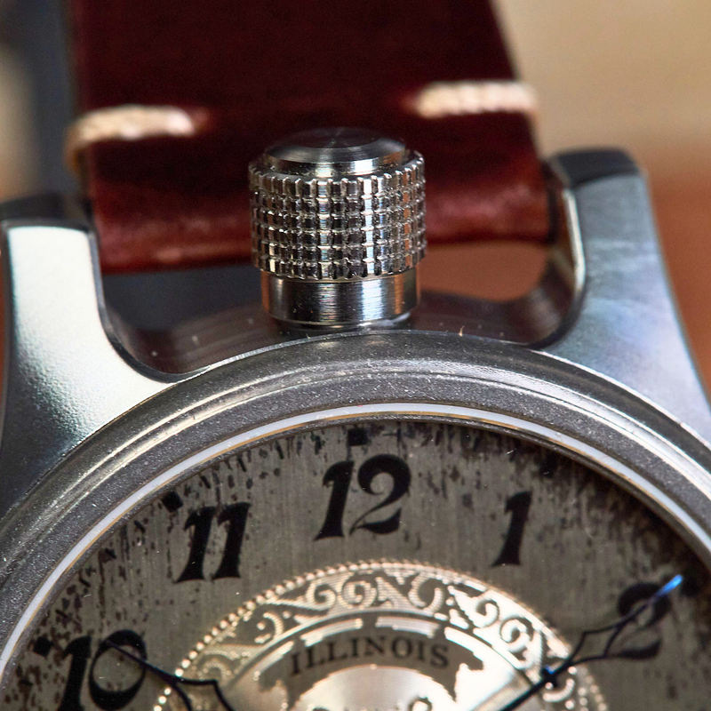 Close-up of a pocket watch with 'Illinois' branding on a wooden background