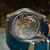 Close-up of a mechanical watch with a blue strap on a blurred background