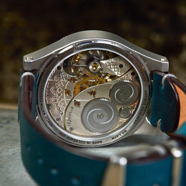 Close-up of a mechanical watch with a blue strap on a blurred background