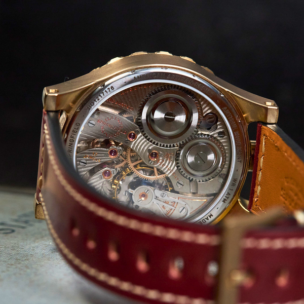 Close-up of a mechanical watch with a red leather strap on a blurred background