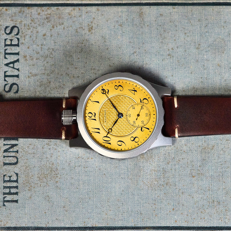A wristwatch with a round silver-tone case, a bright yellow textured dial, and a brown leather strap, laid flat on a textured gray book page with printed text.