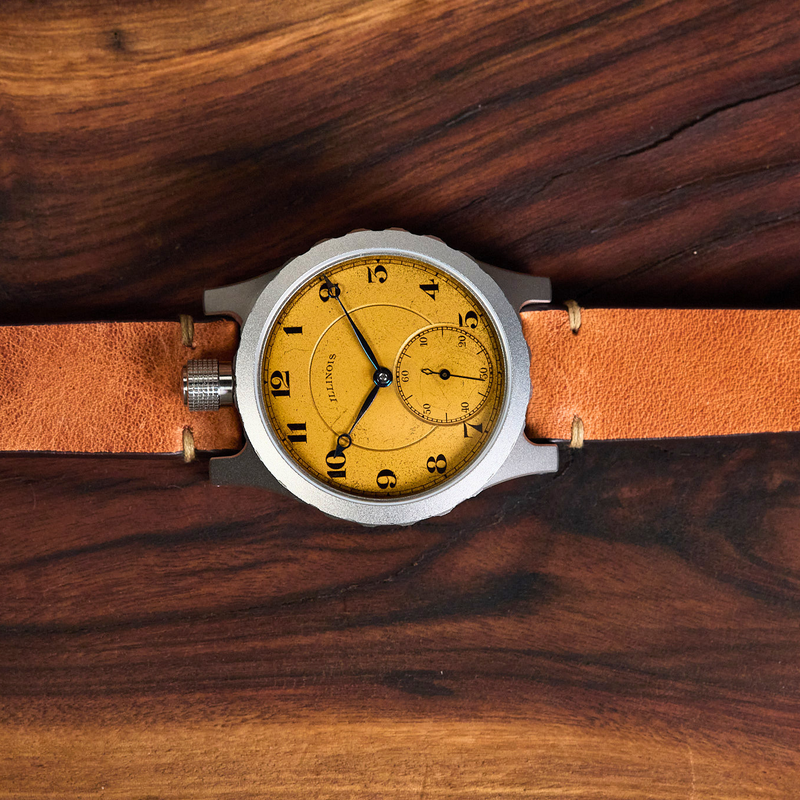 A wristwatch with a round silver-tone case, a yellow dial, and a tan leather strap, laid flat on a dark wood surface.