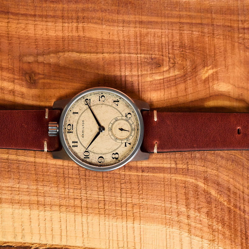 Wristwatch with a brown leather strap on a wooden surface