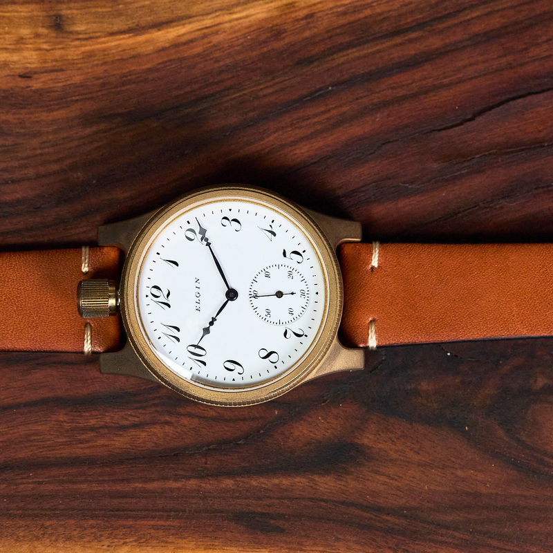 Watch with a brown leather strap on a wooden surface
