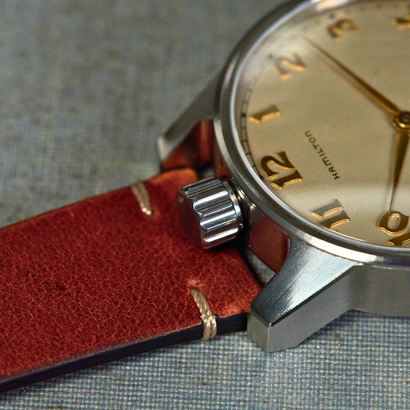 Close-up of a watch with a red strap on a textured surface