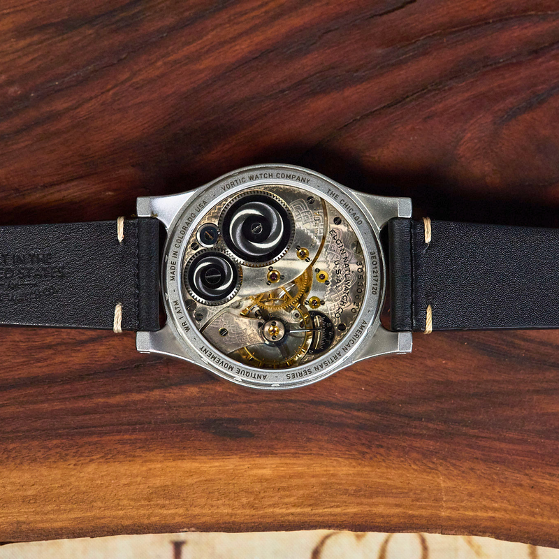 Watch with a visible mechanical movement on a wooden surface