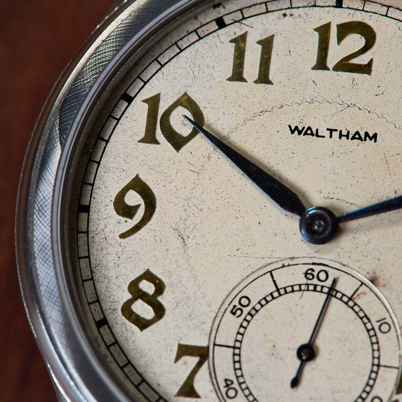 Close-up of an old Waltham watch face with visible wear.