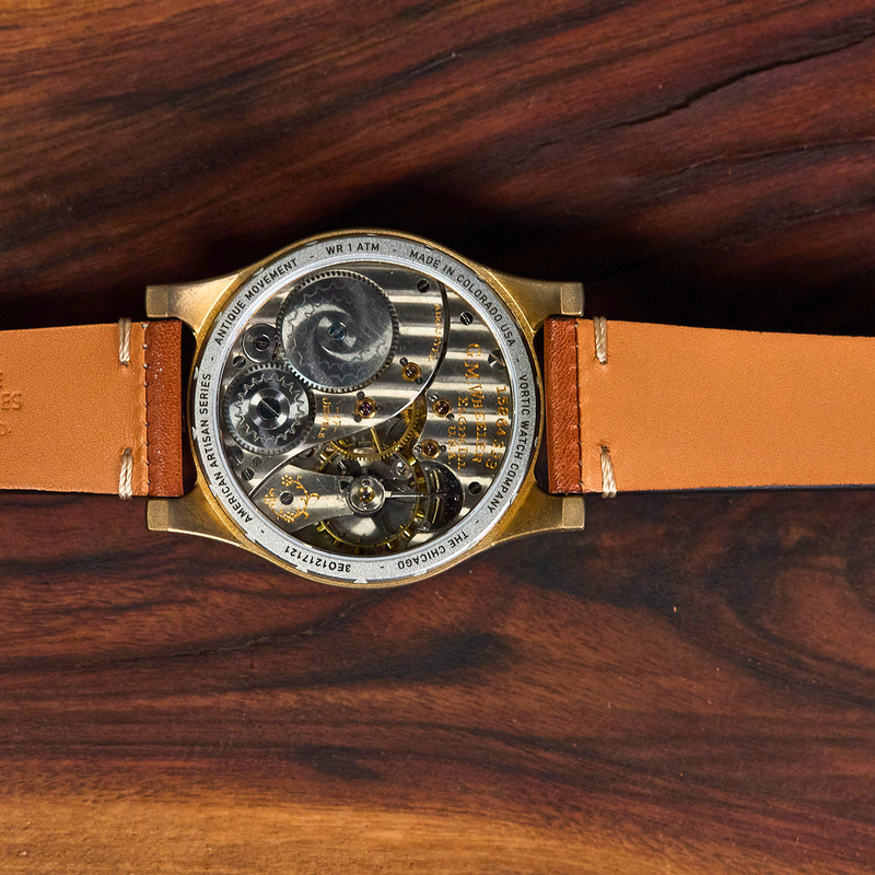 Watch with a brown leather strap on a wooden surface