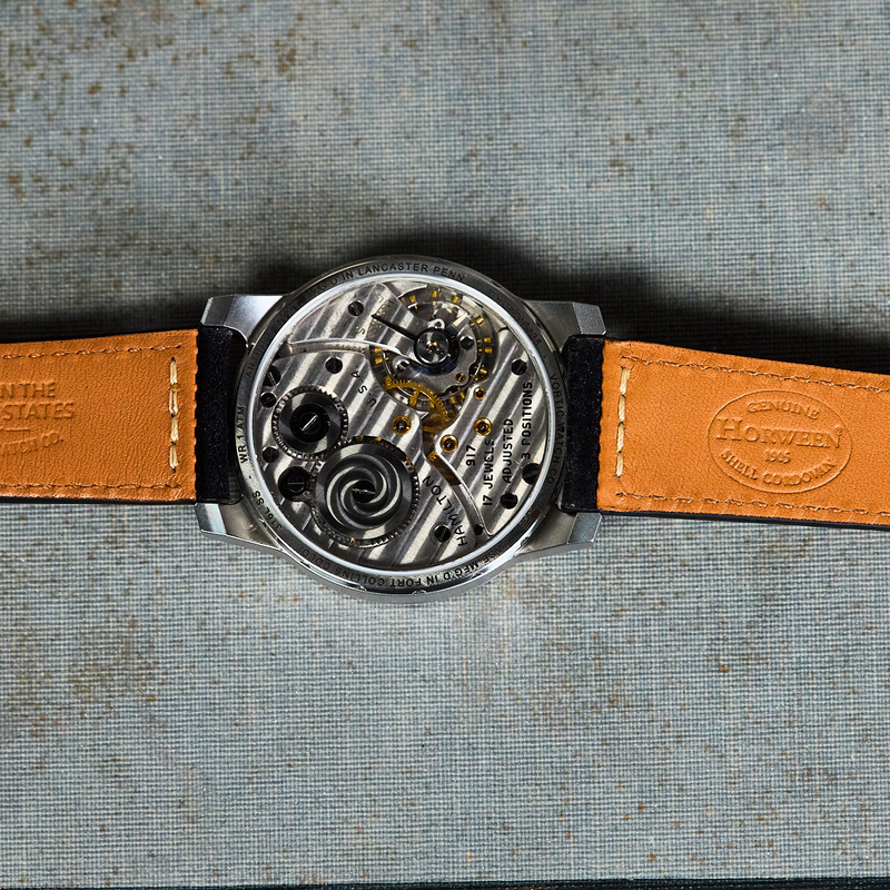Watch with a brown leather strap on a textured surface