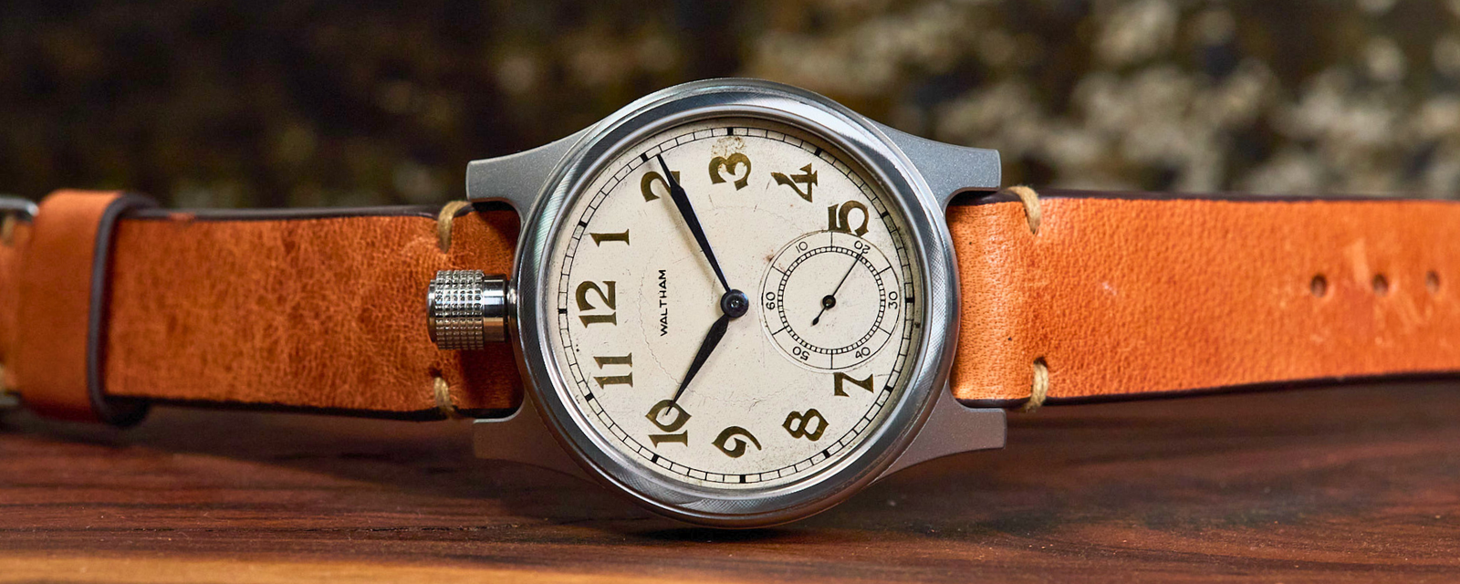 Vintage-style watch with orange leather strap on a wooden surface