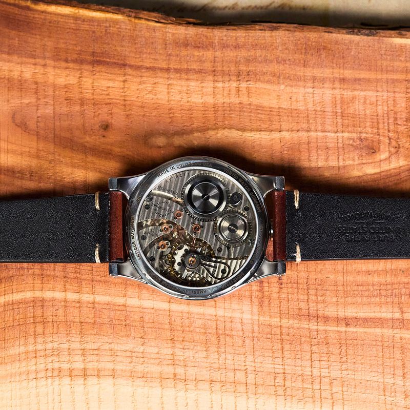 Watch with a black strap on a wooden surface