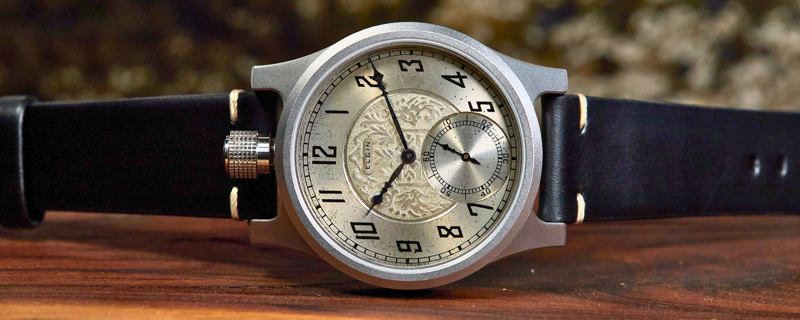 Vintage-style wristwatch with black leather strap on a wooden surface