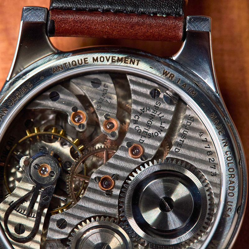 Close-up of a mechanical watch with visible movement on a wooden surface