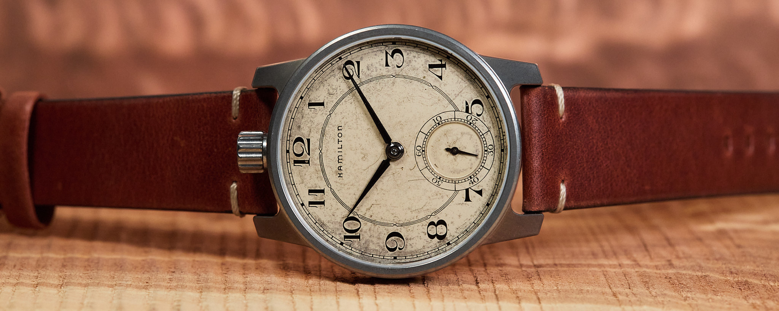 Vintage-style watch with brown leather strap on a wooden surface
