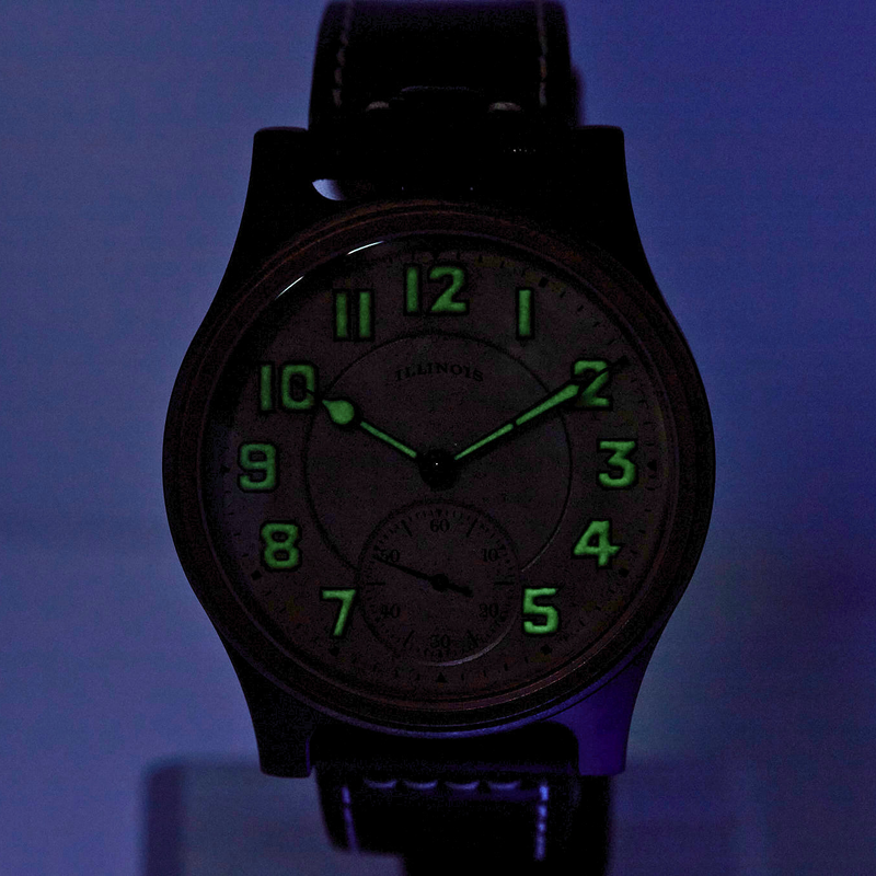 A black analog wristwatch with a dark dial and bright green luminous numerals and hands, shown against a blue-lit background.
