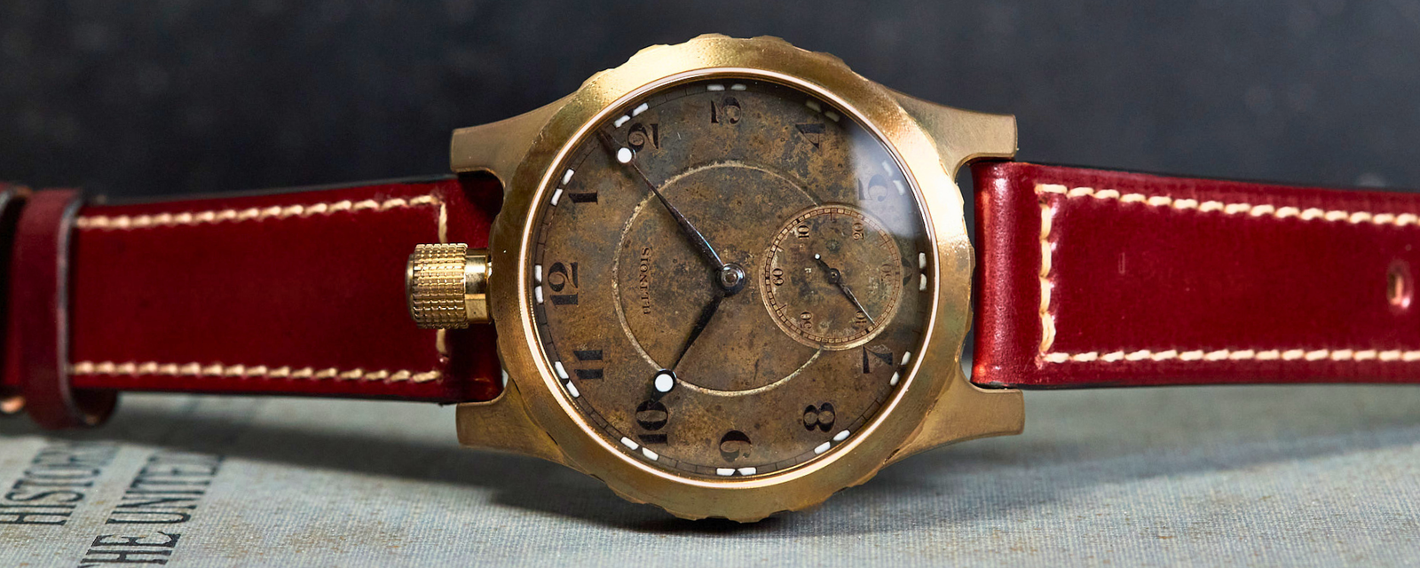 Vintage-style watch with red leather strap on a textured surface